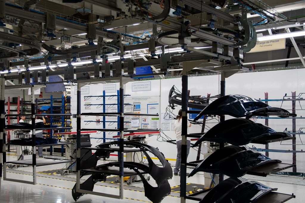 Defensas de automóvil colgadas en espera delante de la línea de pintura